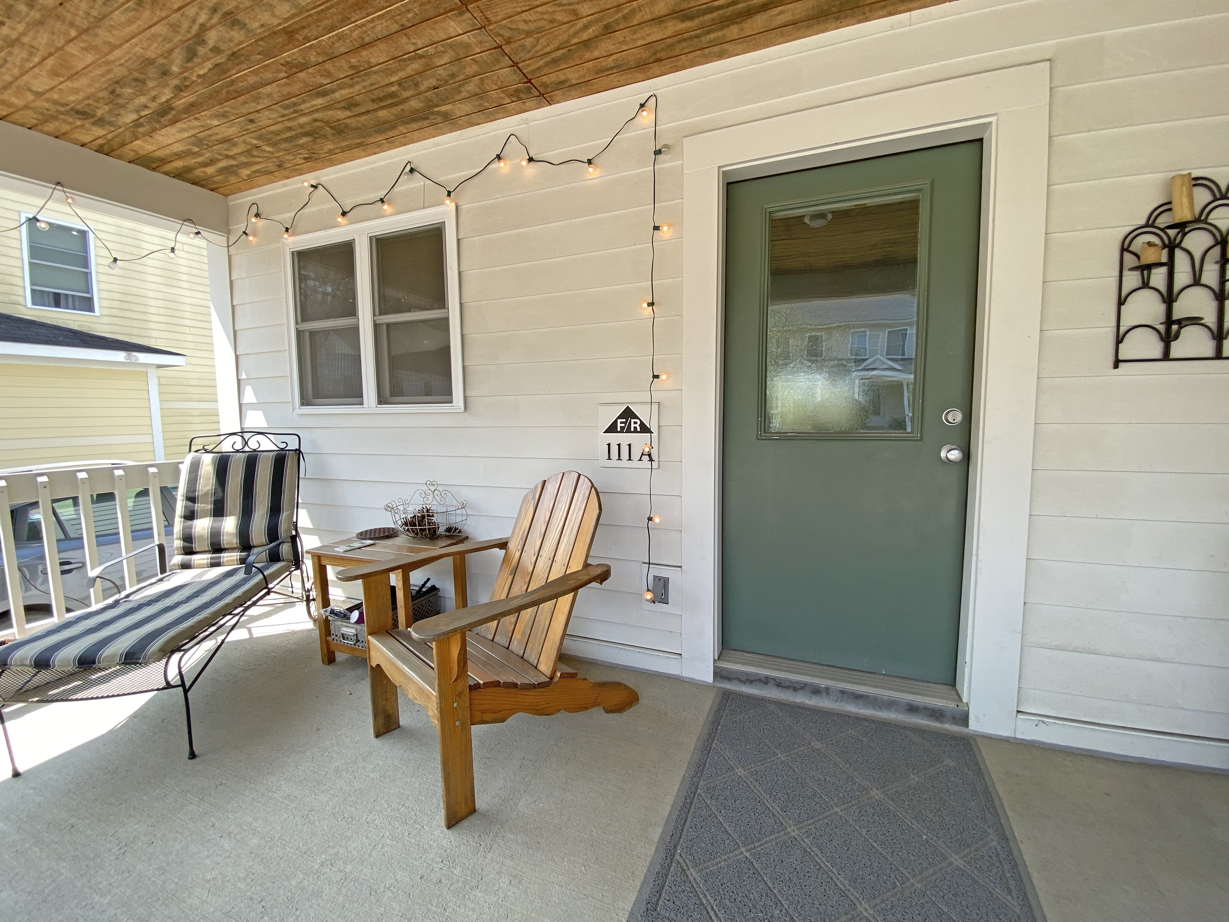 Image of a porch with a green door and mismatched chairs 